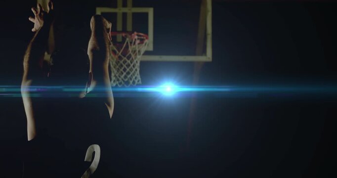 Sports basketball player holding ball low before spotlight flaring behind hoop and initiating shot