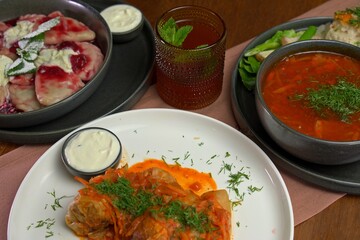 Traditional Eastern European lunch with stuffed cabbage rolls, borscht, sweet cherry dumplings, sour cream, and iced tea garnished with mint.