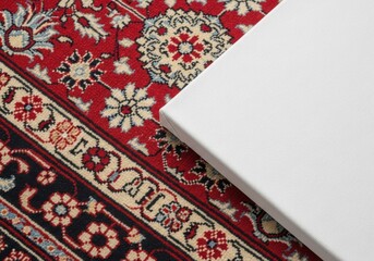 A white canvas placed on a vibrant, detailed red oriental rug, ready for art.