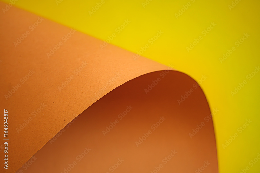 Poster close-up studio shot of an orange sheet of paper gracefully curved against yellow backdrop. highligh