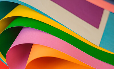 Close-up of curled sheets of colored paper. The composition emphasizes shape and negative space. Making it useful as a minimal design and modern background. Selective focus.