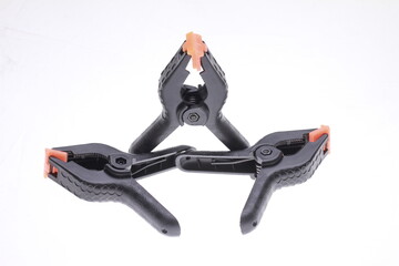 Black plastic spring clamps on a white background.