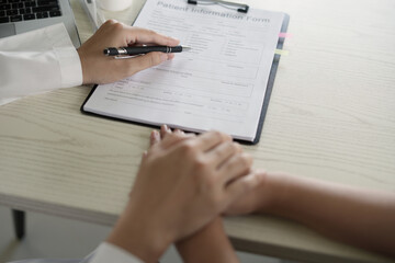 An asian psychiatrist or healthcare professional female doctor is gently holding patient hand comforting and encouragement, reassuring woman, only hands close up. Mental health care support concept.