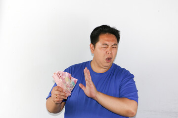 Asian guy holding indonesian rupiah and saying no with rejection gestuuue to the money
