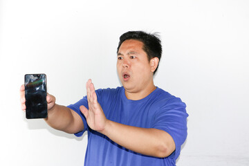 Young asian guy with refusal gesture holding mobile phone