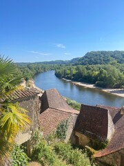 Fototapeta premium Ancient red stone architecture with blooming flower boxes and scenic river vistas in a medieval French village.