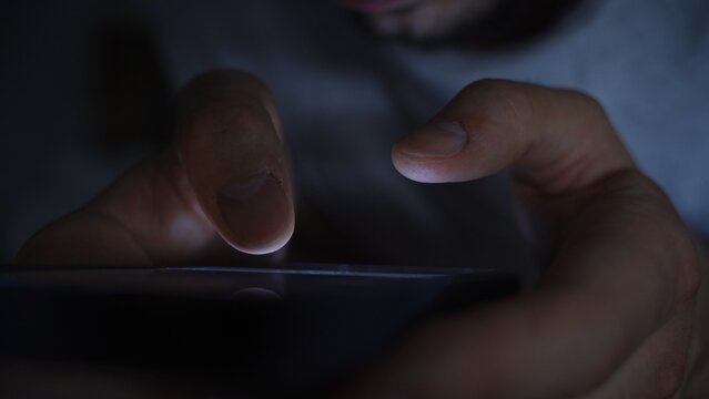 Smartphone and social network addiction concept. Hands using smartphone in bed at night