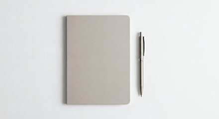 A minimalist top-down view of a closed grey notebook and a silver pen on a white background.