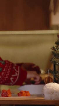 Vertical video. Woman in Red Sweater Working with Dough Near Christmas Tree with White and Red Dough Balls on Table