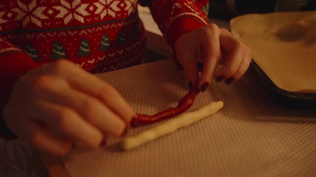 Woman in Festive Sweater Rolling Dough Stick on Silicone Mat Near Baking Tray Lined with Parchment
