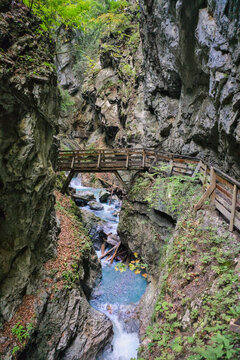Wolfsklamm, Austria: A view inside the Wolfsklamm gorge, showing a wooden walkway and stairs built along a rugged, rocky cliff face with a turquoise stream flowing below