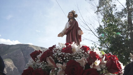 Small image of the Sacred Heart of Jesus carried in a basket, with the sky and sun rays in the background