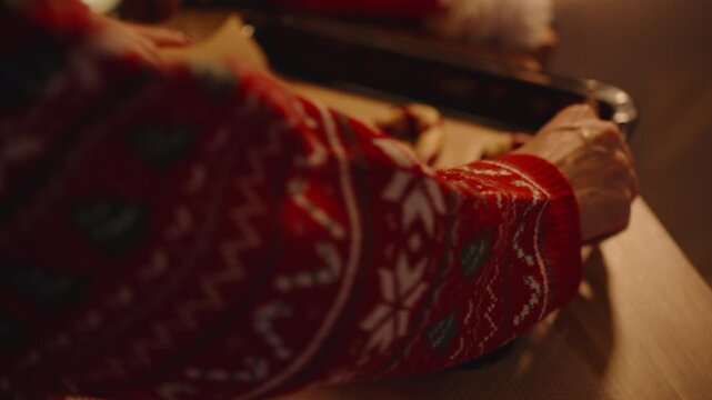 Woman Reaches Toward Tray with Shaped Candy Cane Cookies in Warm Light with Santa Hat Nearby