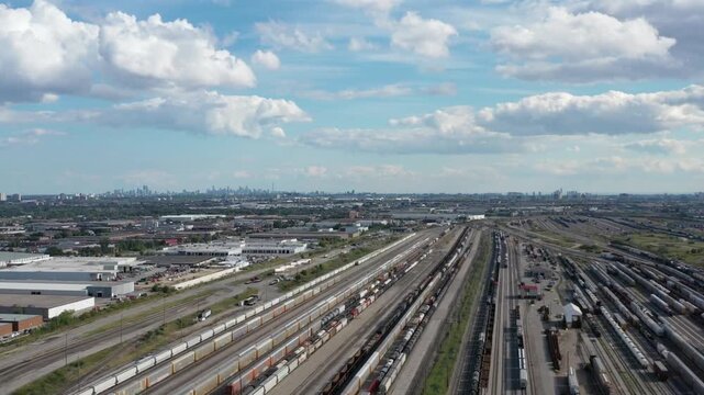 Aerial view of a vast railroad yard with trains and city skyline in background