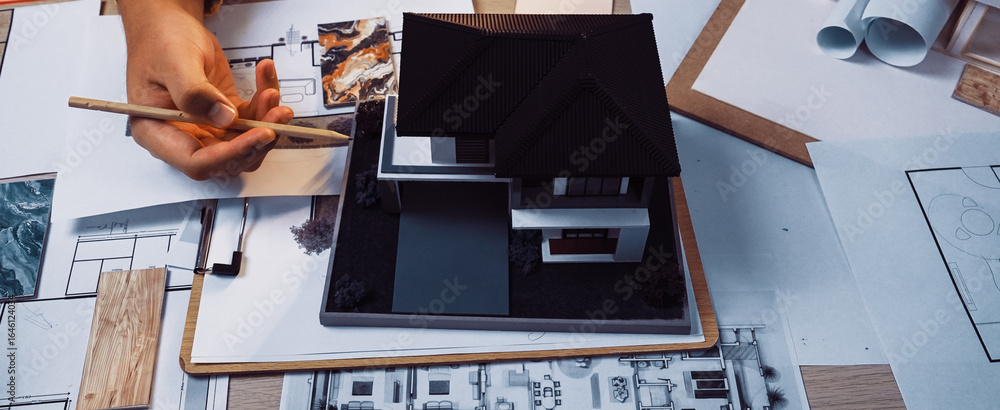 Poster a creative workspace featuring hands working on an architectural model, surrounded by sketches, blue