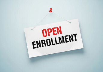 Photo of a sign hanging on a blue wall announces the start of the open enrollment period for a program