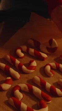 Vertical video. Woman Holding Tray of Freshly Baked Candy Cane Cookies Over Cooling Rack with Both Hands