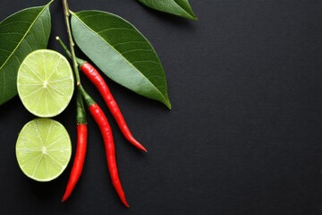 Lime slices and chili peppers arranged on a dark background.