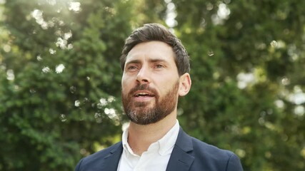 Happy joyful businessman in a formal suit relaxing with closed eyes standing in urban city park. A smiling handsome bearded male breathes deeply, savoring fresh air, enjoys being in nature. Close up - Powered by Adobe