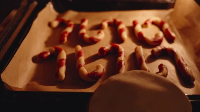 Woman Sliding Tray of Raw Red and White Candy Cane Cookies into Oven from Side Angle