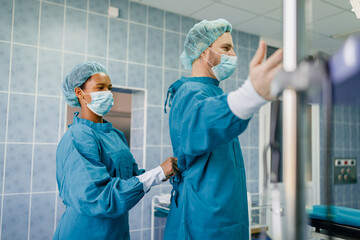 Team of Skilled Surgeons in Blue Surgical Attire Preparing for a Procedure in a Sterile Operating...