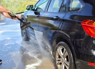 A man washes his car at a self-service station.