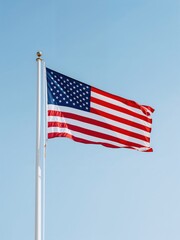 United States flag waving on a flagpole against a clear blue sky