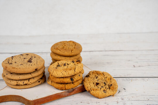 Stack of oatmeal raisin, peanut butter and chocolate chip cookies on a wood cutting board 
