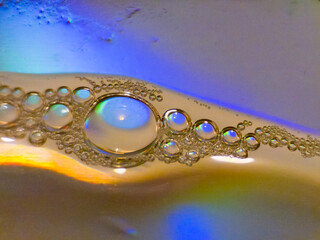 Close-up abstract of oil bubbles floating on water with colorful reflections