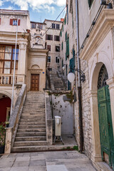 Narrow street with an ancient stone staircase and historic buildings in the old town, Croatia.Labyrinthine backstreets featuring traditional stone architecture, weathered facades, and steep stairs