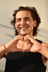 Man Making Heart Gesture with Hands, Smiling, and Radiating Positivity