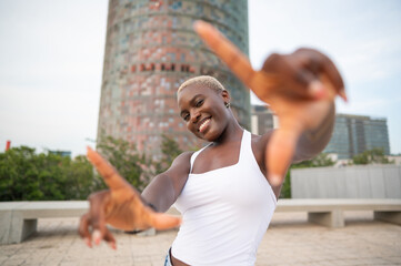Smiling black woman framing with hands in barcelona cityscape with agbar tower