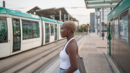 Young woman waiting for the tram at the station in the city