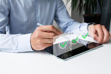 Close-up of a businessman’s hand using a pen to create a digital checkmark on a virtual hologram...