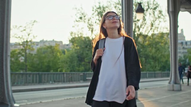 Woman walking through Bir Hakeim Bridge in Paris France with classic cityscape and charming buildings showcasing iconic landmarks in French tourism and travel