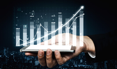 A close-up view of a hand holding a smartphone displaying a financial chart with upward growth,...