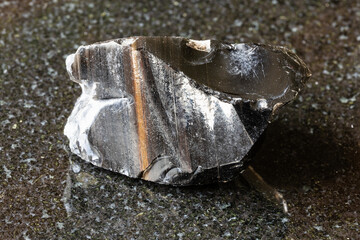 sample of raw striped obsidian mineral on black