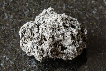 sample of rough pumice rock on black granite