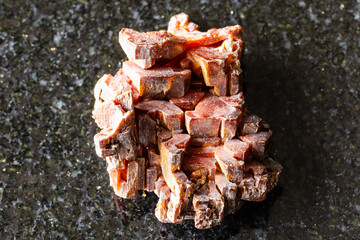 sample of rough vanadinite rock on black granite