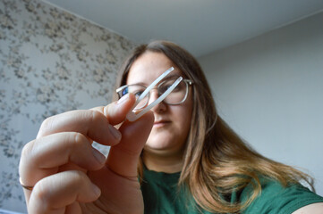 young woman long hair glasses putting contact lenses on holding lens case and lens in her hands...