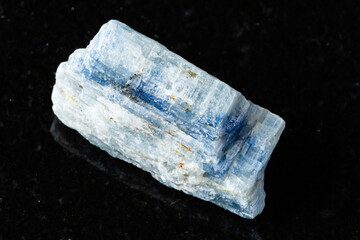 sample of uncut kyanite rock on black granite