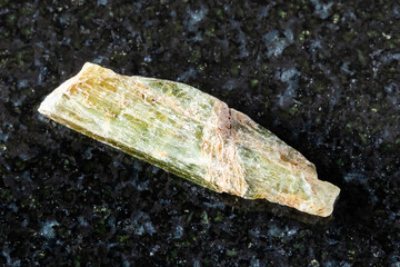sample of rough epidote crystal on black granite