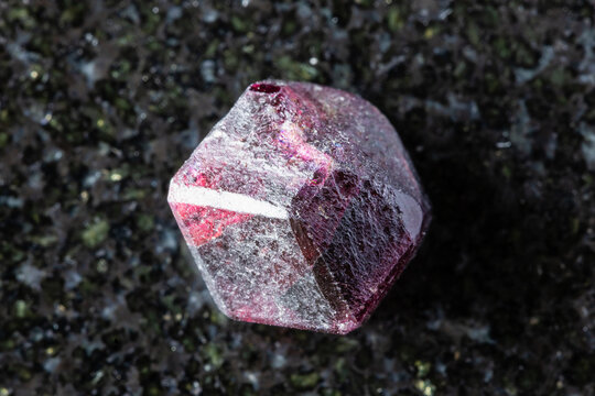 sample of rough rhodolite pyrope crystal on black