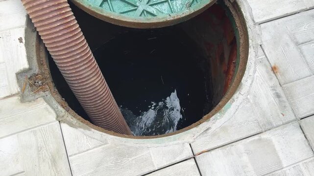 Technicians are engaged in servicing a septic system, inspecting and cleaning the drainage pit. Septic tank service. Sewage Tank truck.