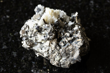 sample of raw arsenopyrite rock on black granite