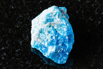 sample of unworked apatite rock on black granite