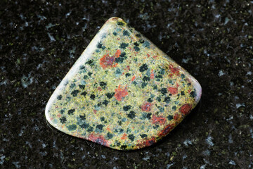 sample of polished epidosite rock on black granite