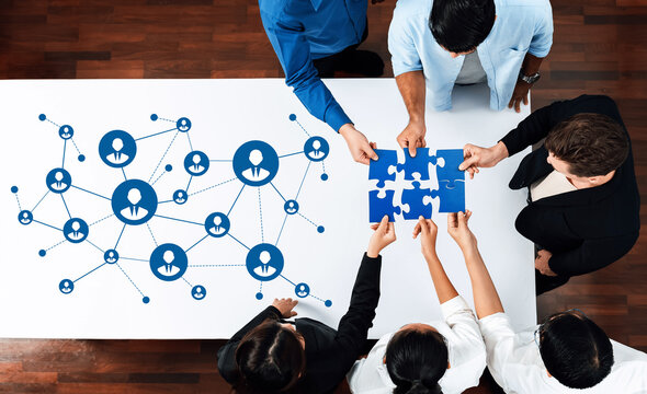 This image illustrates a collaborative networking scenario where diverse professionals work together with puzzle pieces, emphasizing teamwork and the importance of connections. Amity