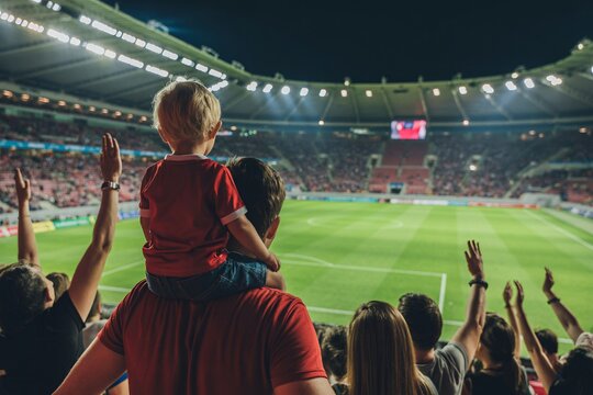 Excited young boy on dad's shoulders enjoys soccer game with cheering crowd and vibrant stadium lights - Powered by Adobe
