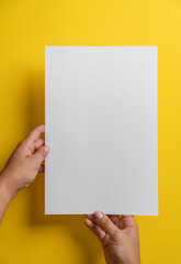 Hands Holding Blank White Sheet on Yellow Background
